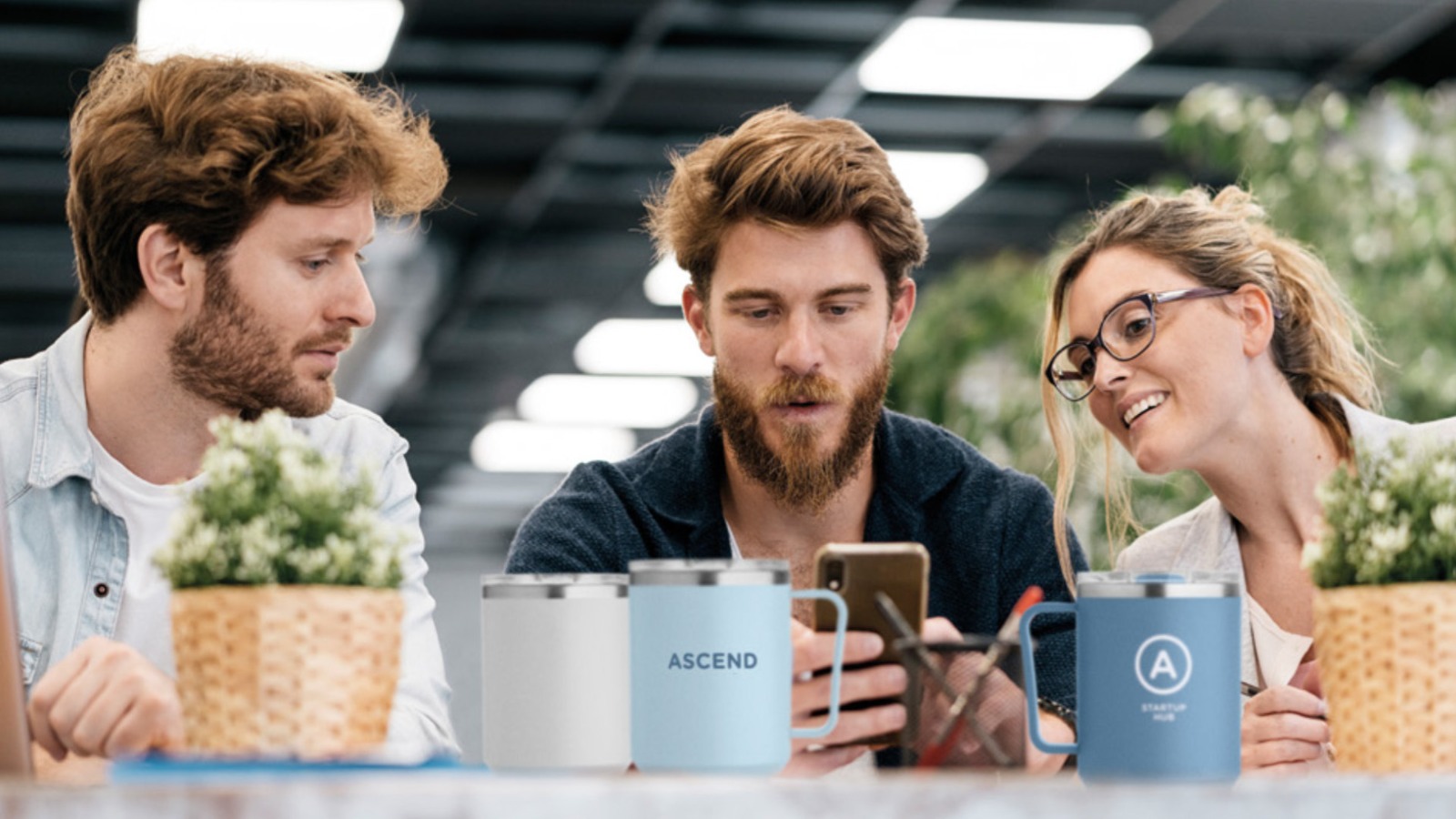 Personalized thermal mugs with corporate branding in a modern collaborative workspace